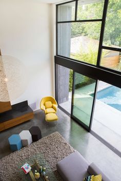 an aerial view of a living room with modern furniture and large windows overlooking the pool