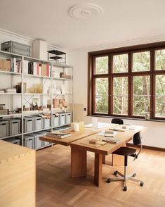 an office with wooden floors and shelves filled with books, papers, and other items