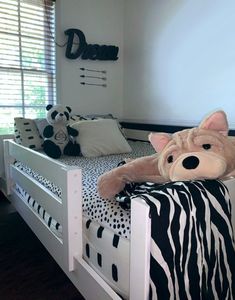 a teddy bear sitting on top of a bed in a room with black and white decor