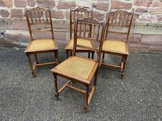 four wooden chairs sitting next to each other in front of a brick wall