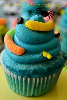 a cupcake with blue frosting and sprinkles in the shape of a worm