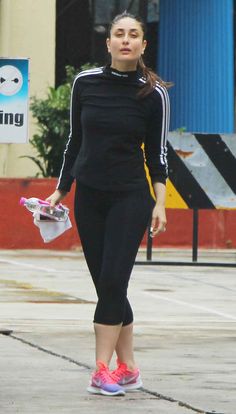 a woman walking down the street with her hand in her pocket and wearing pink shoes