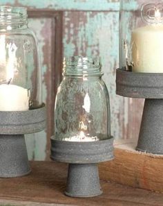 three glass jars with candles in them sitting on a shelf