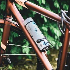 a bicycle with a water bottle strapped to the handlebars and seatposts