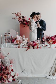 a bride and groom standing in front of a table with flowers