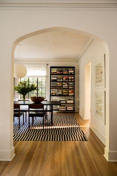 an archway leads into a dining room with black and white checkered rug on the floor