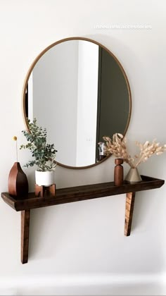 a mirror and some vases on a shelf in front of a wall mounted mirror