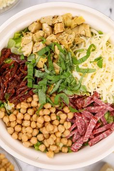 a white bowl filled with meat, beans and veggies on top of a table