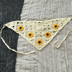 a crocheted triangle with sunflowers on it sitting on top of a bed