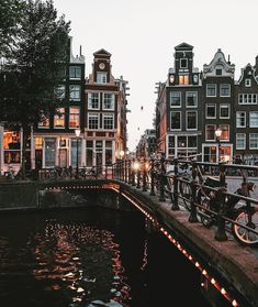 bicycles parked on the side of a bridge over a river in front of some buildings