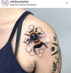 a woman's shoulder with a tattoo of a bee and honeycombs on it