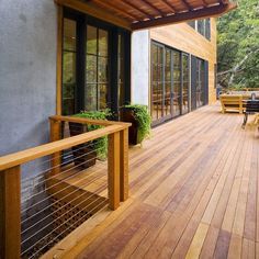 a wooden deck with metal railing and chairs