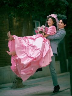 a man carrying a woman in a pink dress