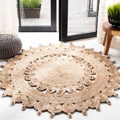 a large round rug on the floor in front of a window with potted plants