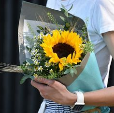 a woman holding a bouquet of sunflowers in her hands