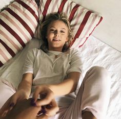 a woman laying in bed next to two pillows