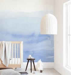 a baby's room with a crib, table and wall mural in the background