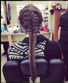 a woman with long hair is sitting in a chair and has her back turned to the camera