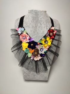 a woman's gray top with flowers and black ribbon around the neck on display