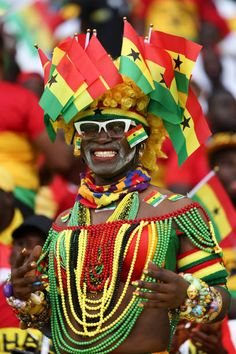 a woman dressed in colorful clothing and headdress at an event with other people behind her