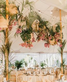 the inside of a tent with tables and chairs covered in white linens, decorated with pink flowers