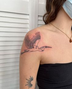 a woman with a bird tattoo on her shoulder and arm, wearing a face mask