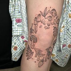 a woman's leg with mushrooms and leaves tattoo on the side of her thigh