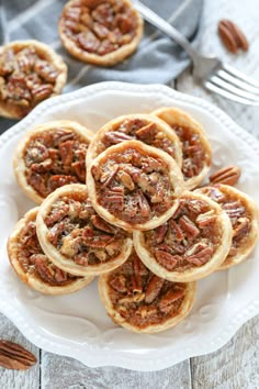 small pecan pies on a white plate with fork and napkin in the background