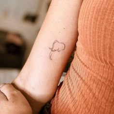 a woman's arm with a small elephant tattoo on the left side of her arm