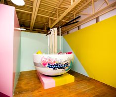 a large bowl sitting on top of a wooden floor next to a yellow and pink wall