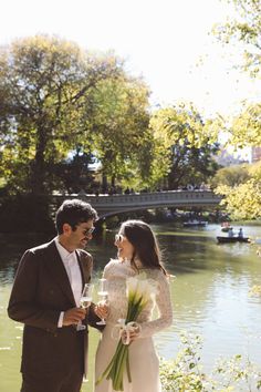 a man and woman standing next to each other in front of a body of water