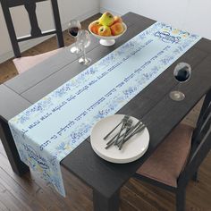 a table set for two with fruit and wine glasses on the table, next to an empty bowl of fruit