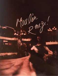 a woman walking down a street next to a carnival ride with the words moulain rouy written on it