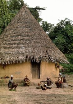 some people are sitting in front of a hut