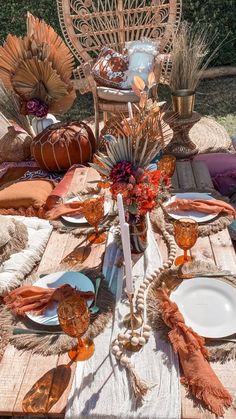 an outdoor table set with plates, napkins and pumpkins on it for thanksgiving dinner