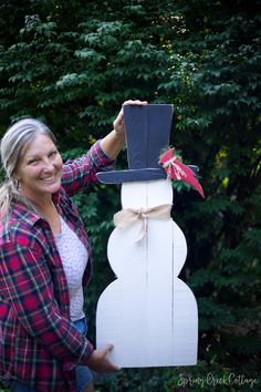 a woman standing next to a wooden snowman