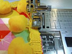 the sewing machine is working on the yellow pom - pom material that has been sewn