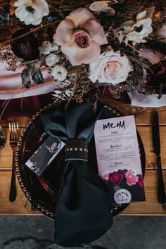 a table setting with black napkins and flowers