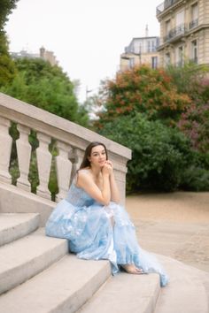 a woman in a blue dress sitting on some steps