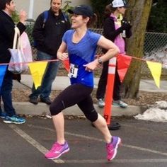 a woman running in a race with other people watching