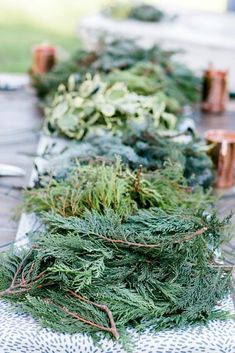 the table is covered with evergreen and other greenery for an outdoor party or gathering