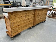 an outdoor bar made out of wood and concrete in a garage with tools on the floor