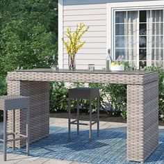 an outdoor table and stools in front of a house