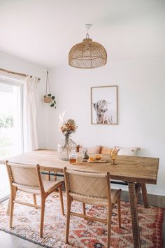 a dining room table with chairs and a rug on the floor in front of it