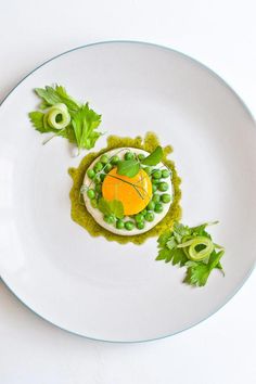 a white plate topped with an appetizer covered in peas and avocado