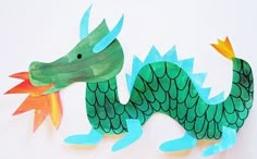 a paper cut out of a green dragon with orange wings on it's head