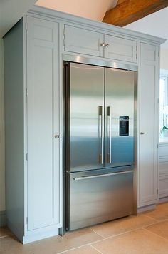 a stainless steel refrigerator and freezer combo in a large kitchen with white cabinetry