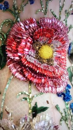 a close up of a flower made out of glass beads and sequins on a piece of cloth