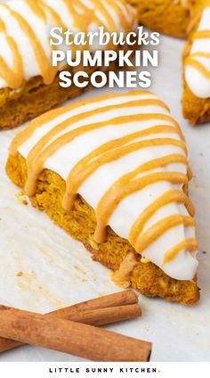 pumpkin scones with white frosting and cinnamon sticks on the side, one slice cut in half