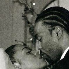 a black and white photo of a man kissing a woman's forehead in front of a christmas tree